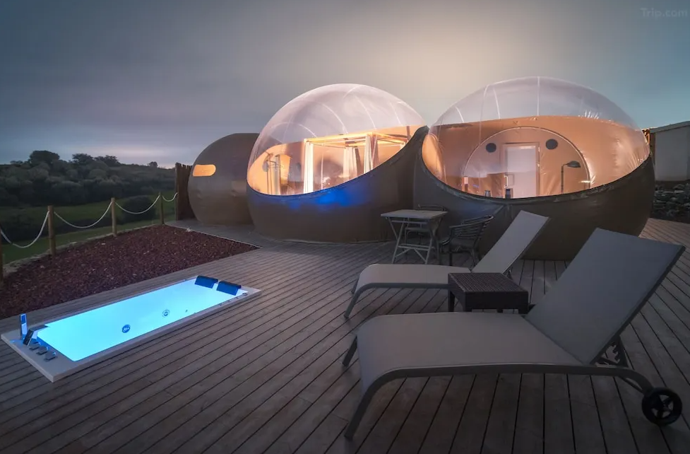 Alojamiento en hotel burbuja Miluna en España con piscina iluminada y terraza al atardecer