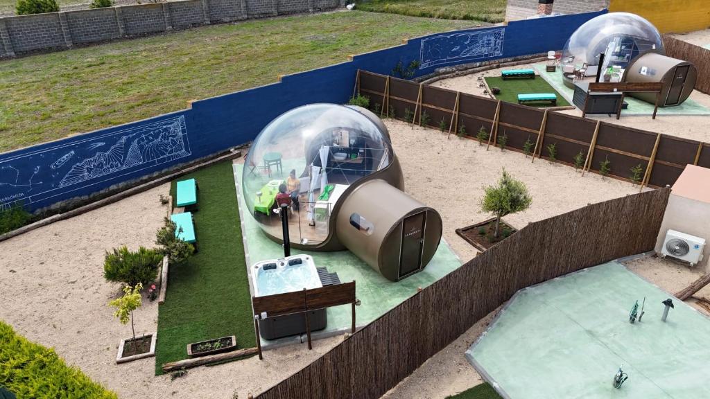 Vista aérea de un complejo de burbujas transparentes para glamping, cada una con su espacio privado, jacuzzi, mobiliario exterior y separaciones con vallas de madera