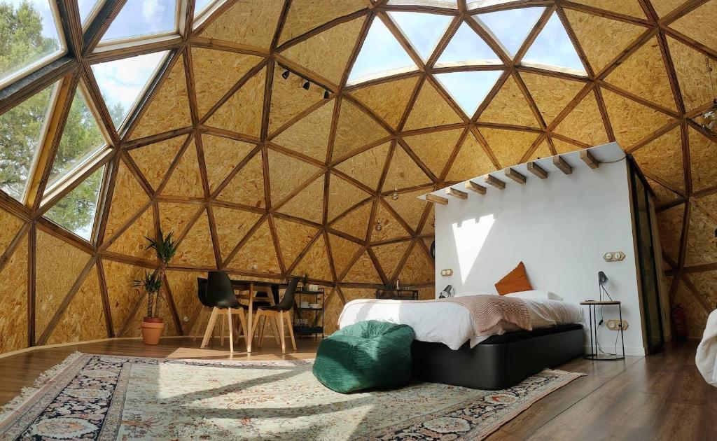 Interior de domo geodésico en Ronda con cama doble, mesa de comedor, alfombra decorativa y abundante luz natural a través del techo acristalado