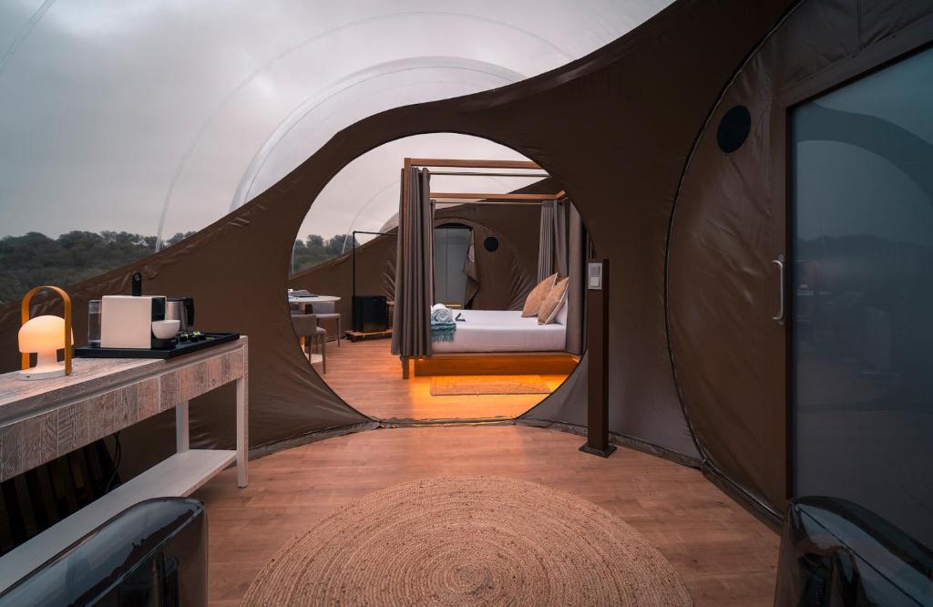 Interior de una habitación de hotel burbuja en España, con cama con dosel, decoración moderna y vistas al exterior a través de la estructura transparente