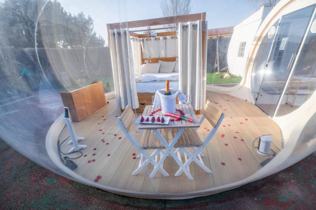 Interior de hotel burbuja con cama con dosel, mesa con botella de champán, fresas, pétalos de rosa y decoración romántica