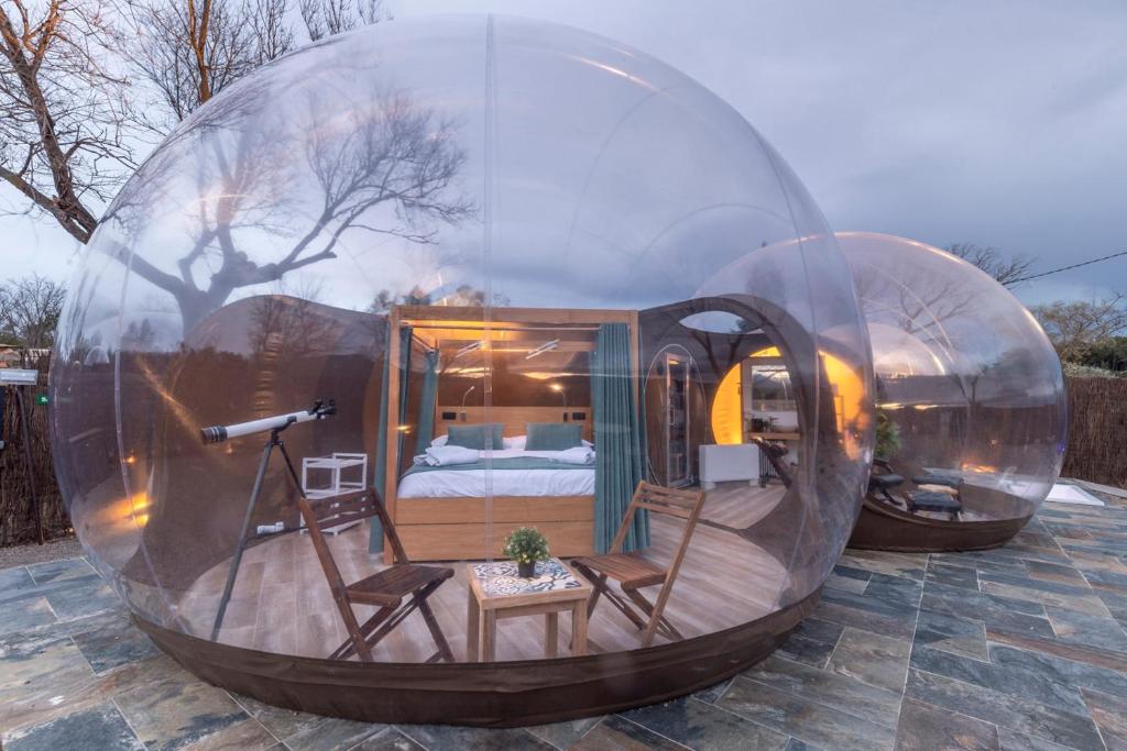 Cúpula transparente con cama doble, telescopio, sillas de madera y decoración minimalista, ideal para observar las estrellas