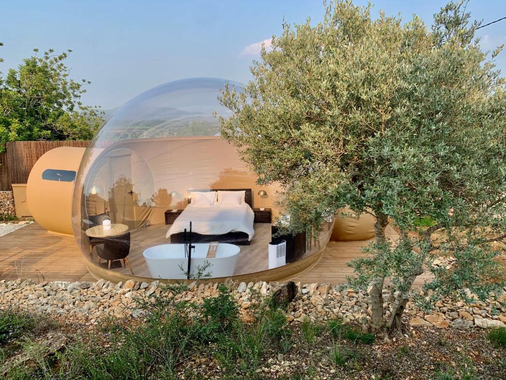 Burbuja de lujo con cama doble, bañera interior y vistas panorámicas a la naturaleza, rodeada de vegetación y piedras naturales