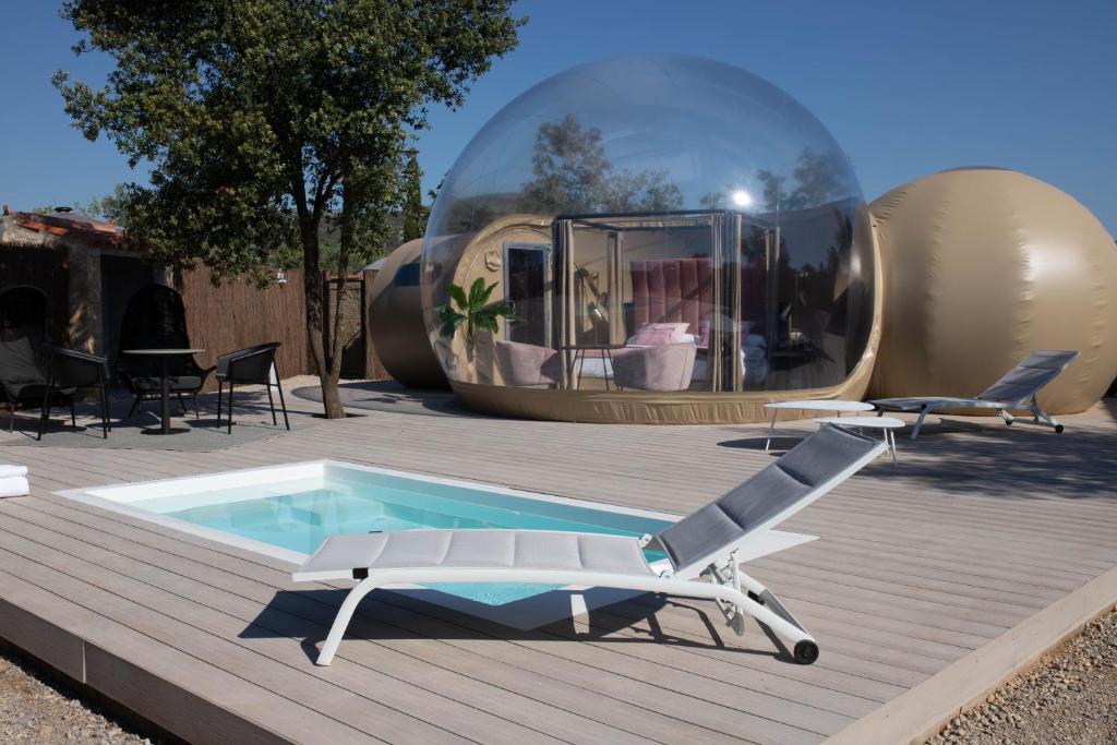 Burbuja de hotel con terraza de madera, piscina privada, tumbonas y zona de estar al aire libre
