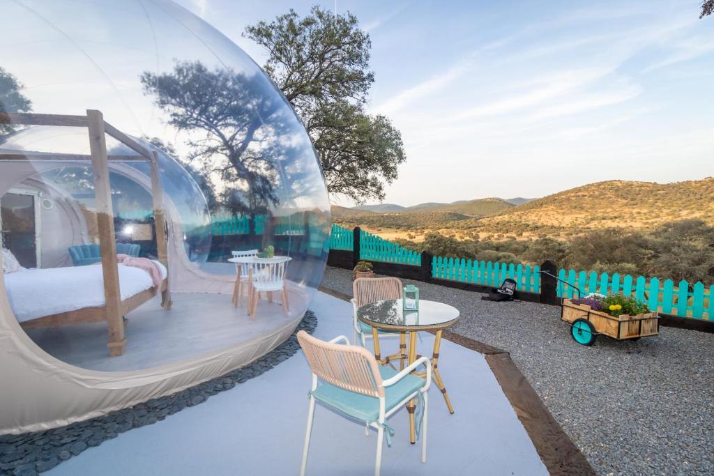 Burbuja transparente con cama doble y terraza al aire libre con vistas panorámicas a las montañas