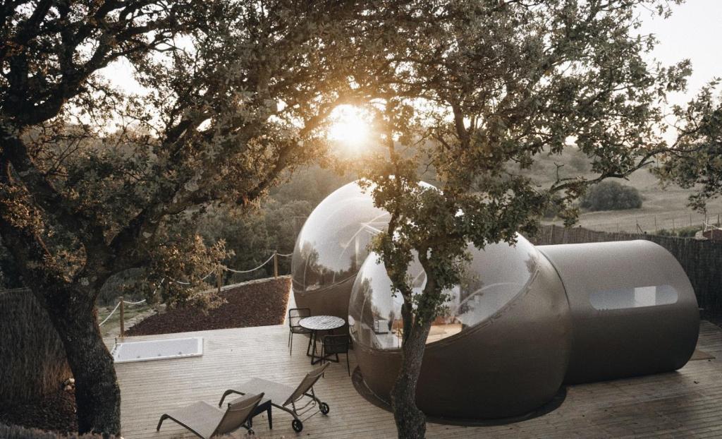 Hotel burbuja con terraza entre árboles, tumbonas y jacuzzi al aire libre al atardecer