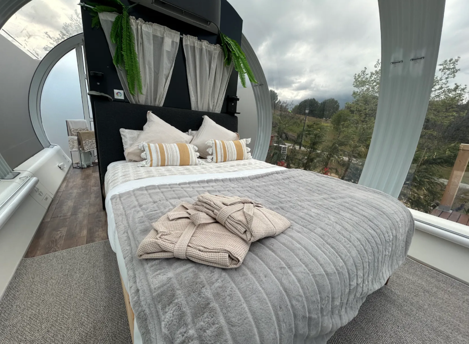 Interior de suite cápsula con cama doble, ventanales panorámicos y albornoces sobre la manta