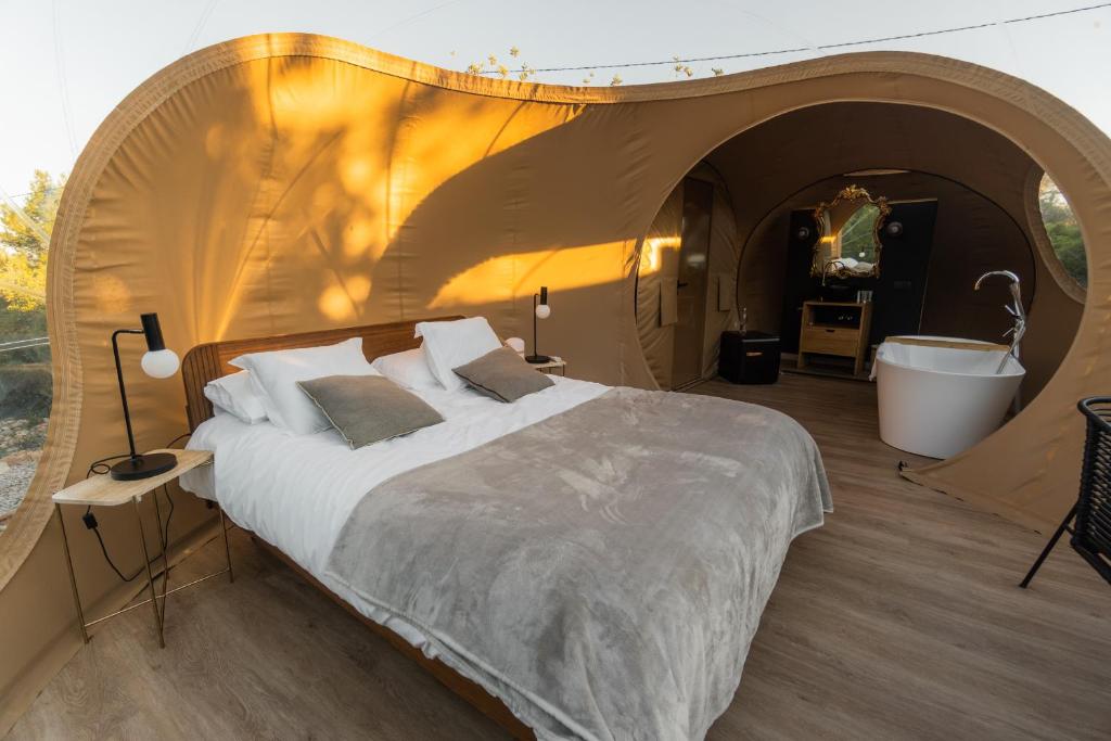 Interior de suite glamping con cama doble, bañera exenta, tocador con espejo dorado y decoración en tonos cálidos