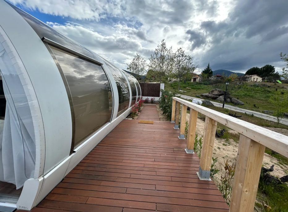Suite panorámica en forma de cápsula con pasarela de madera y vistas a un entorno natural