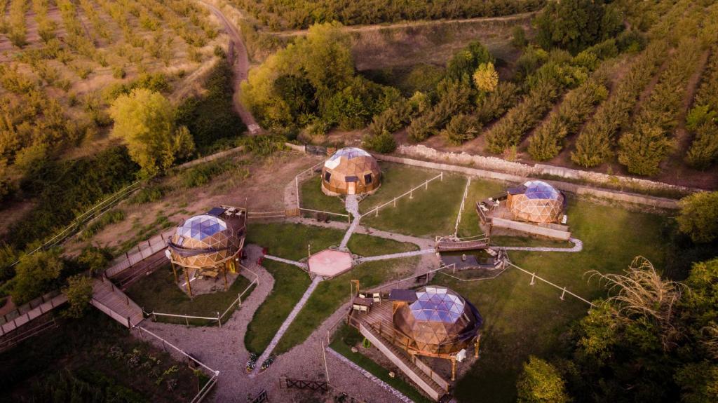 Vista aérea de un hotel burbuja con varios domos de madera rodeados de naturaleza y caminos de piedra