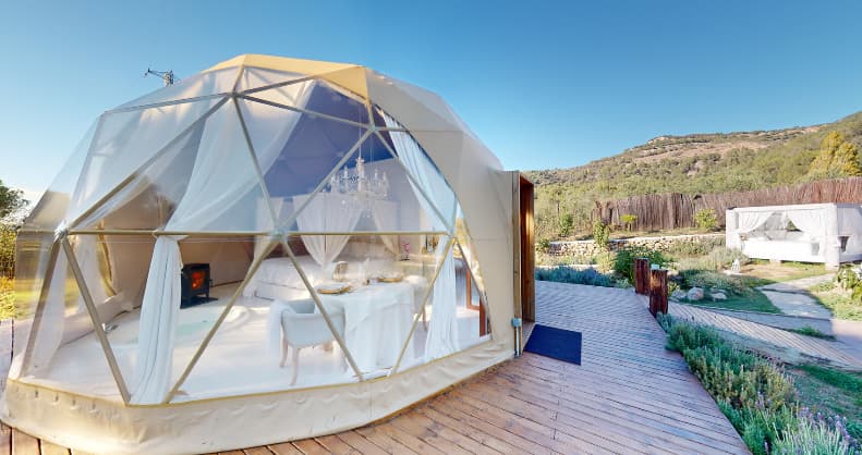 Hotel burbuja de diseño geodésico con interior elegante, terraza de madera y vistas a un entorno natural montañoso
